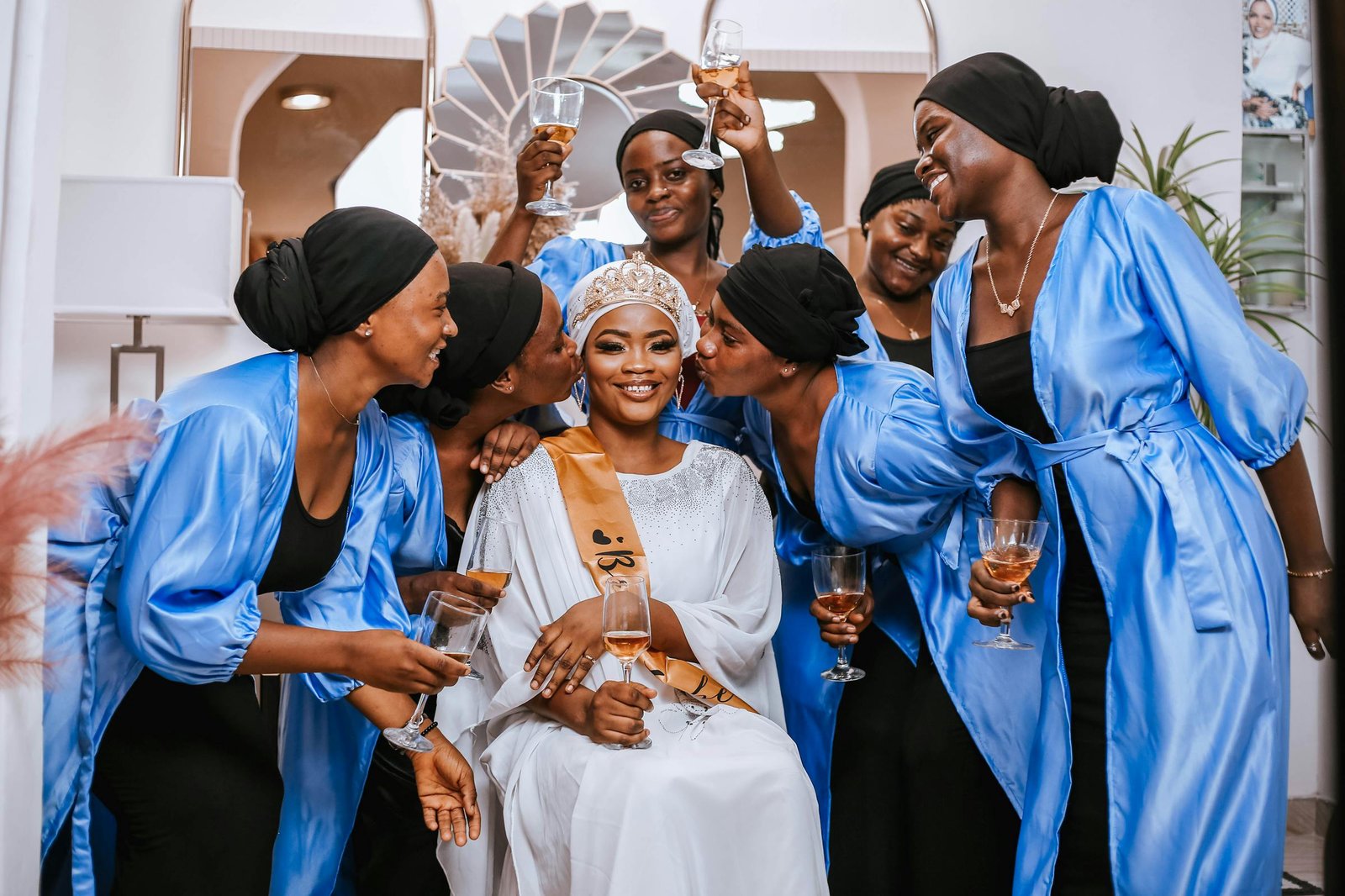 Bride toasting with bridesmaids in coordinated blue robes